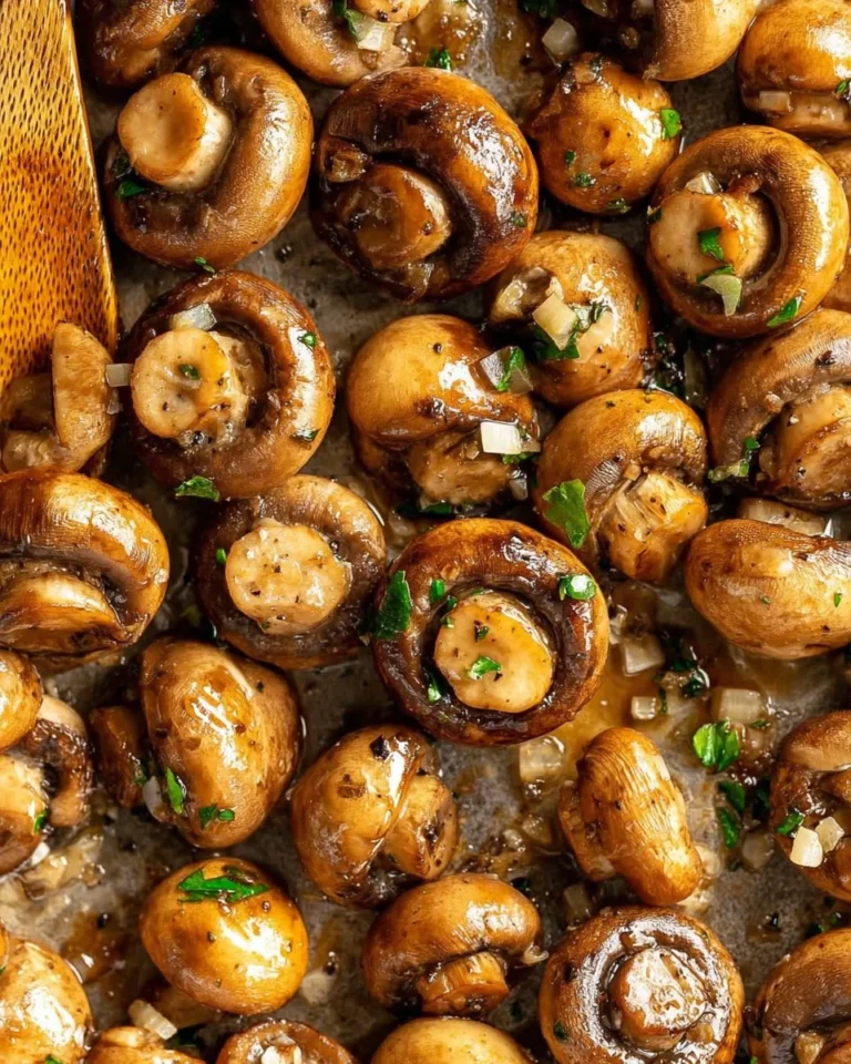 Sautéed garlic mushrooms in a skillet, garnished with herbs.