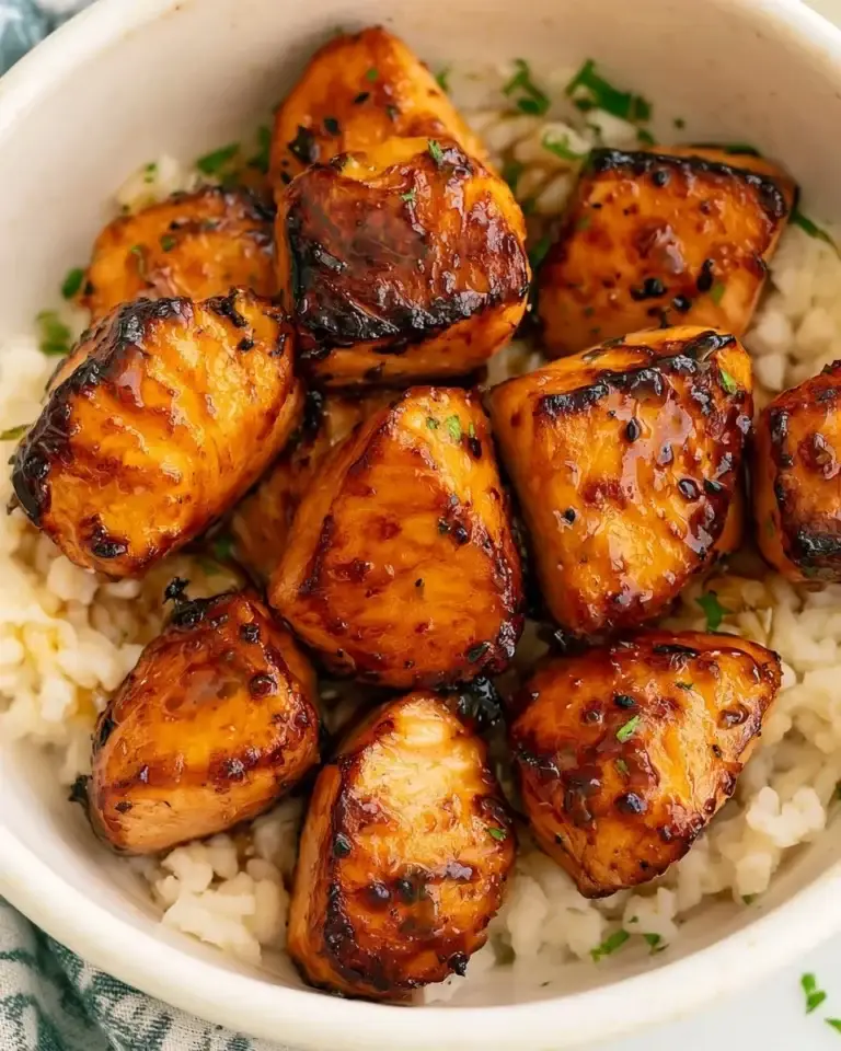 Plate of spicy hot honey salmon bites garnished with herbs.