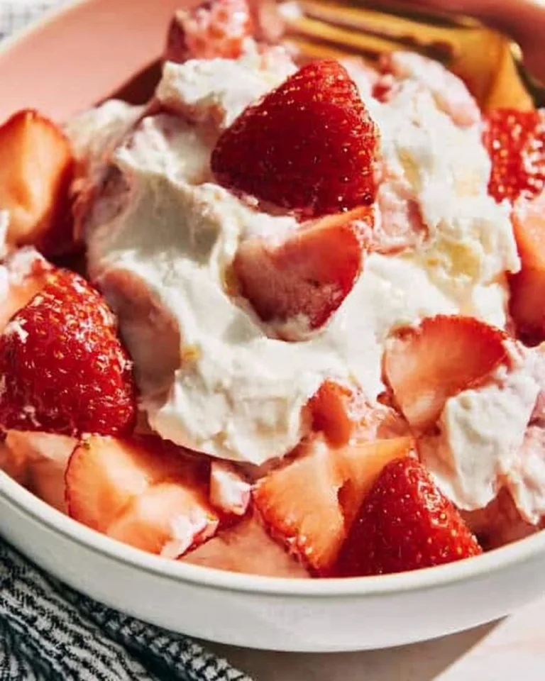 Strawberry cheesecake salad topped with fresh strawberries and cheesecake bites.