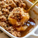 Bowl of easy apple crisp topped with vanilla ice cream and caramel sauce.